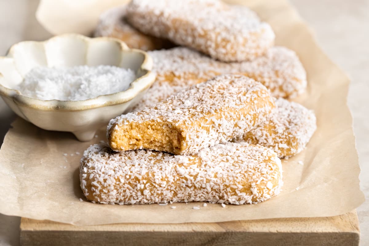 Homemade clean protein bars coated in coconut on a wooden board