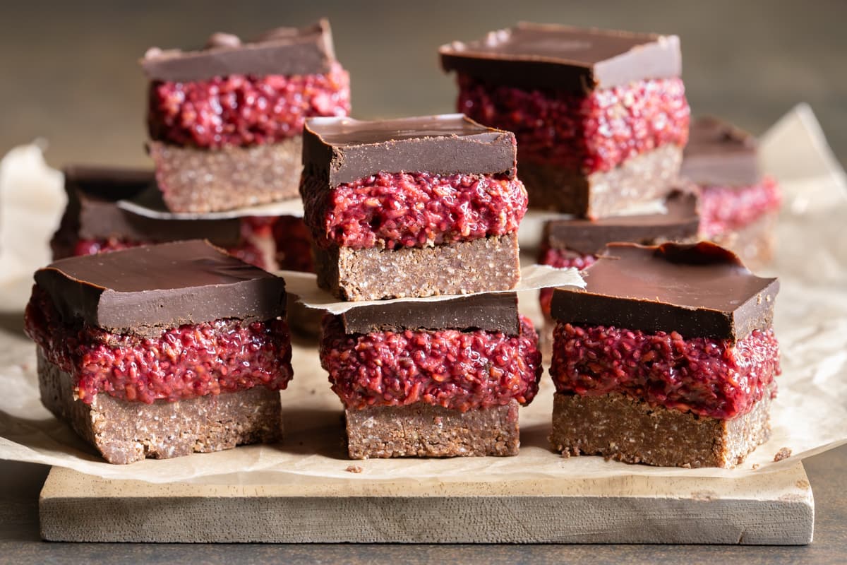 Easy chocolate raspberry chia slice on a wooden board lined with a sheet of baking paper