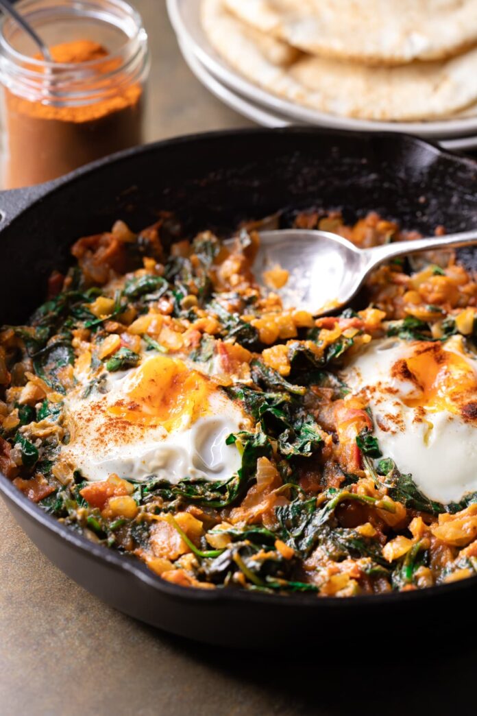 Healthy shakshuka with fresh tomato and spinach served with flatbread