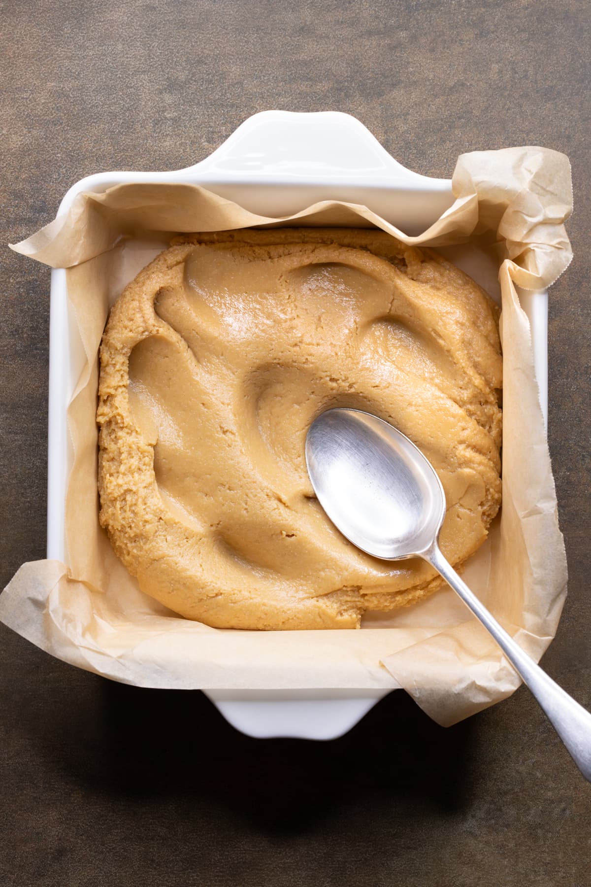 Dough for four ingredient vegan peanut butter bars pressed into a square dish