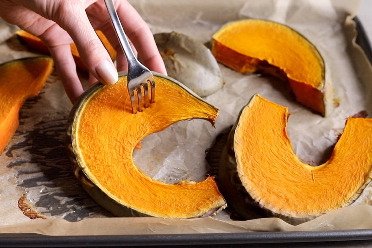 Baked pumpkin slices with a fork piercing one slice