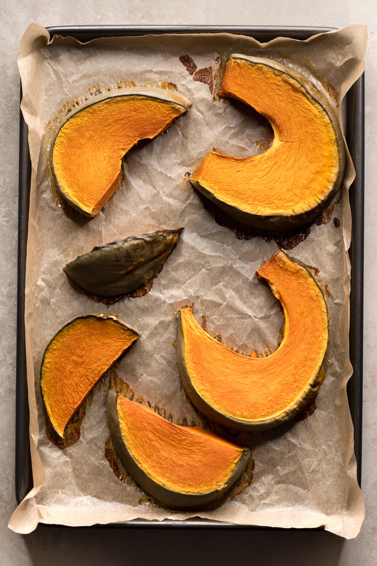 Slices of baked pumpkin on a baking tray lined with baking paper