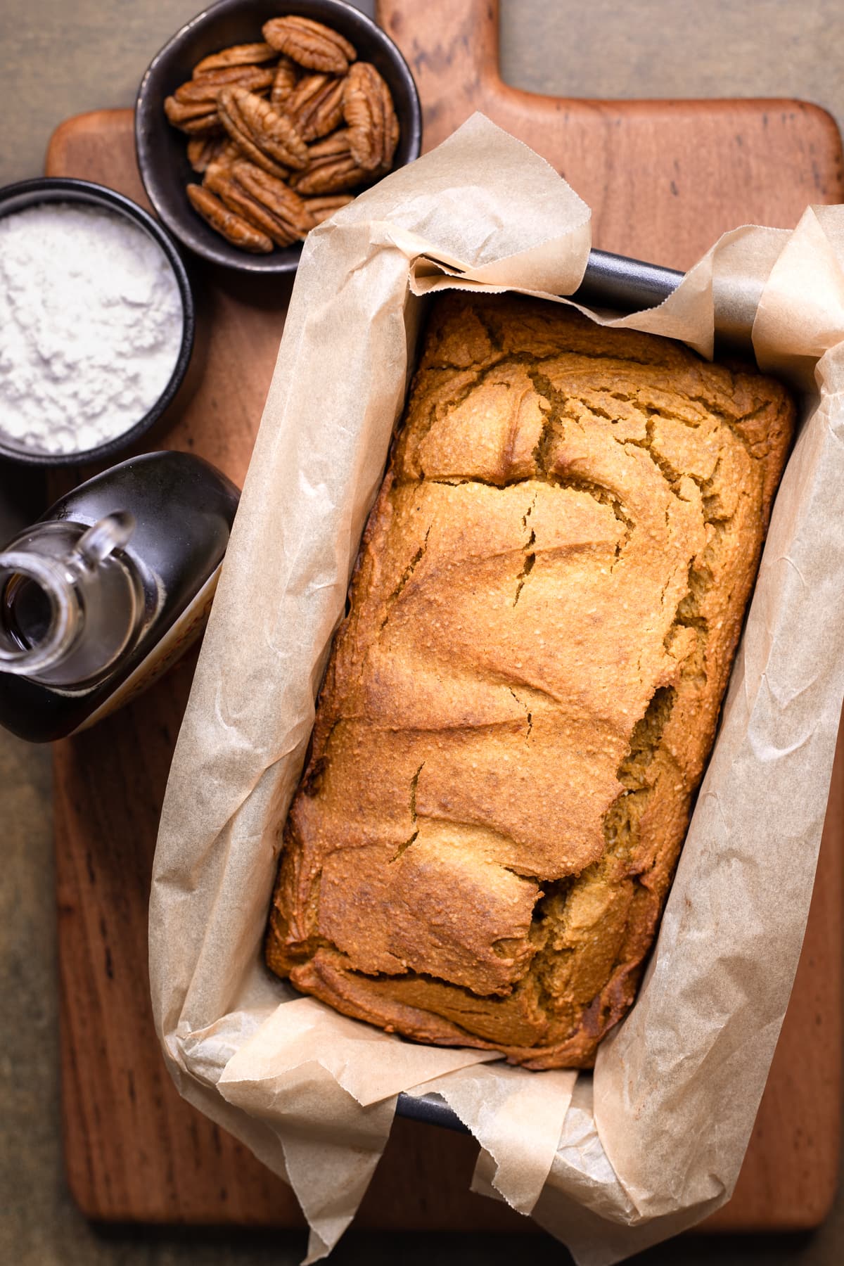 Gluten-free pumpkin bread in a loaf tin with ingredients for maple glaze