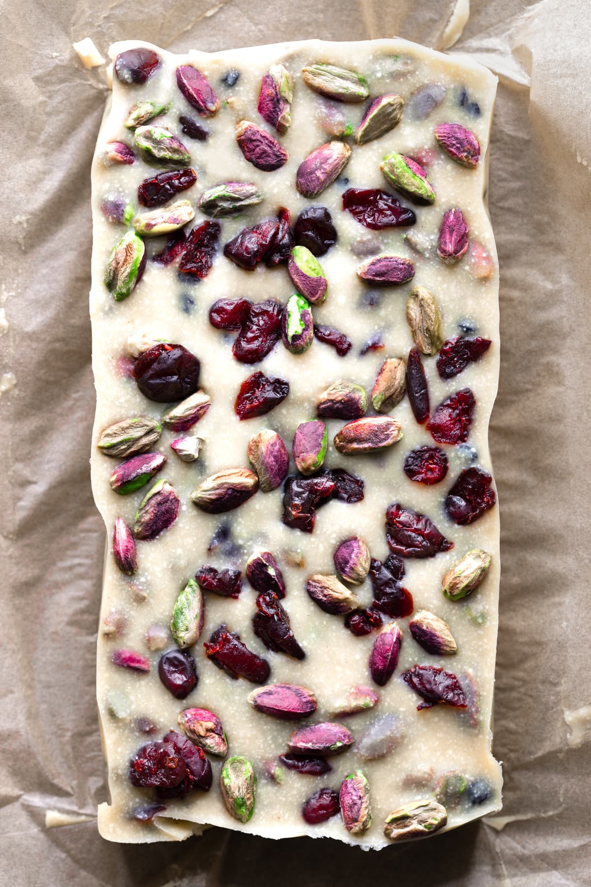 A slab of gourmet white christmas slice with pistachio nuts and cranberries