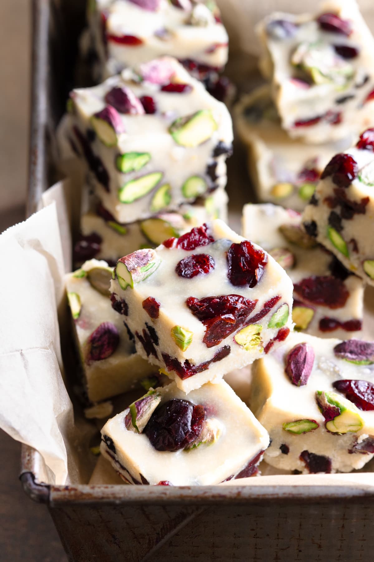 Pieces of gluten-free vegan white christmas slice arranged in a tin