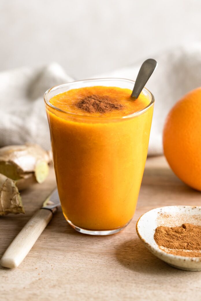 Orange ginger carrot smoothie topped with cinnamon powder