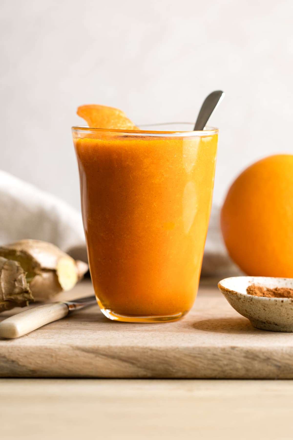 Orange ginger carrot smoothie served in a glass with a garnish of orange peel