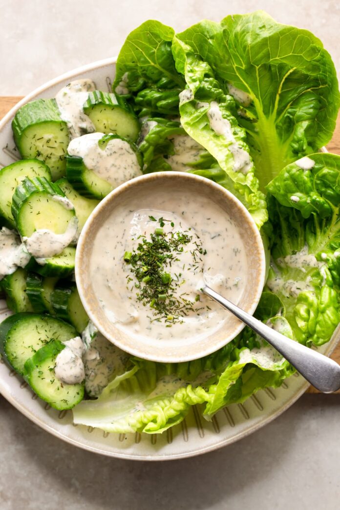 Creamy vegan tahini ranch dressing garnished with dried green herbs