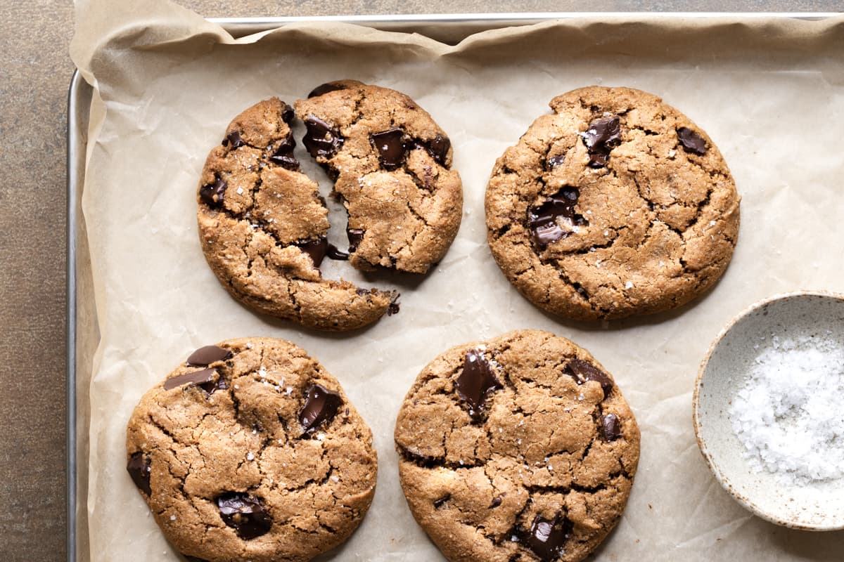 A tray of chocolate chip cookies with a bowl of sea salt