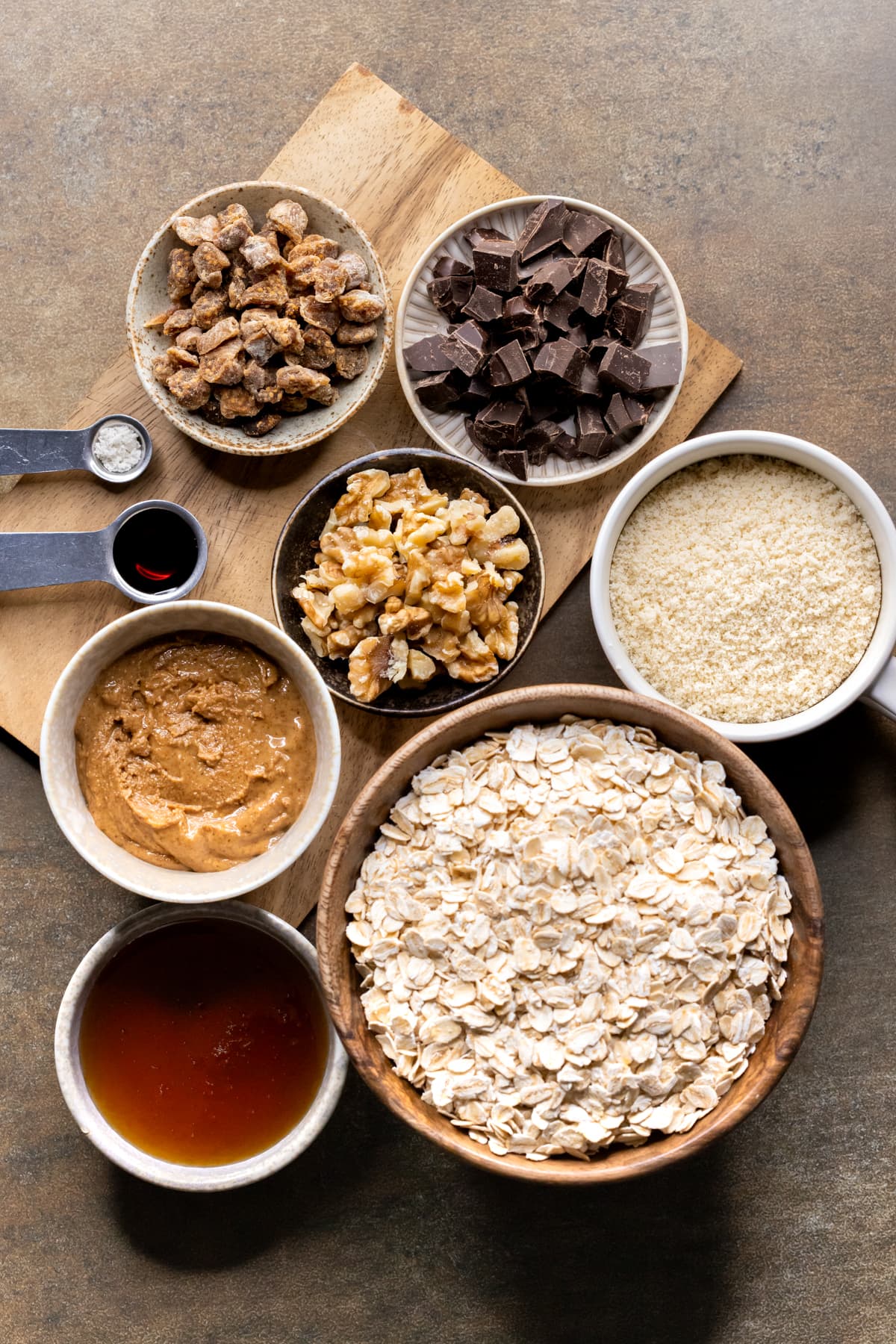 Ingredients for baked oatmeal breakfast bars set out in bowls on a wooden board