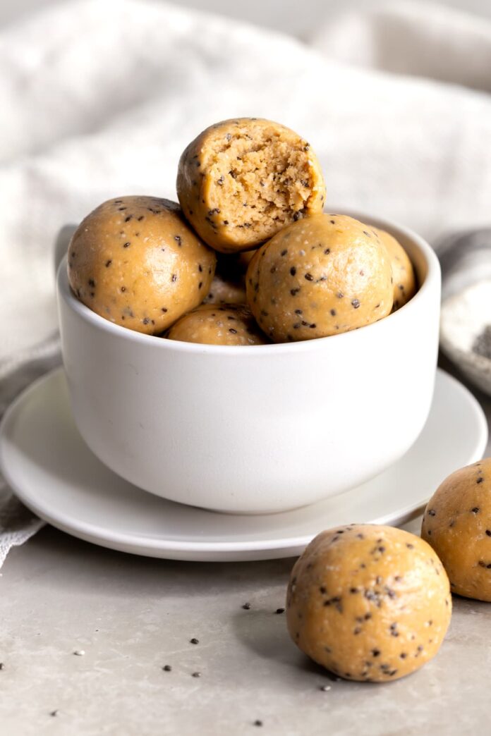 Peanut butter energy balls stacked in a bowl with a bite taken out of one ball