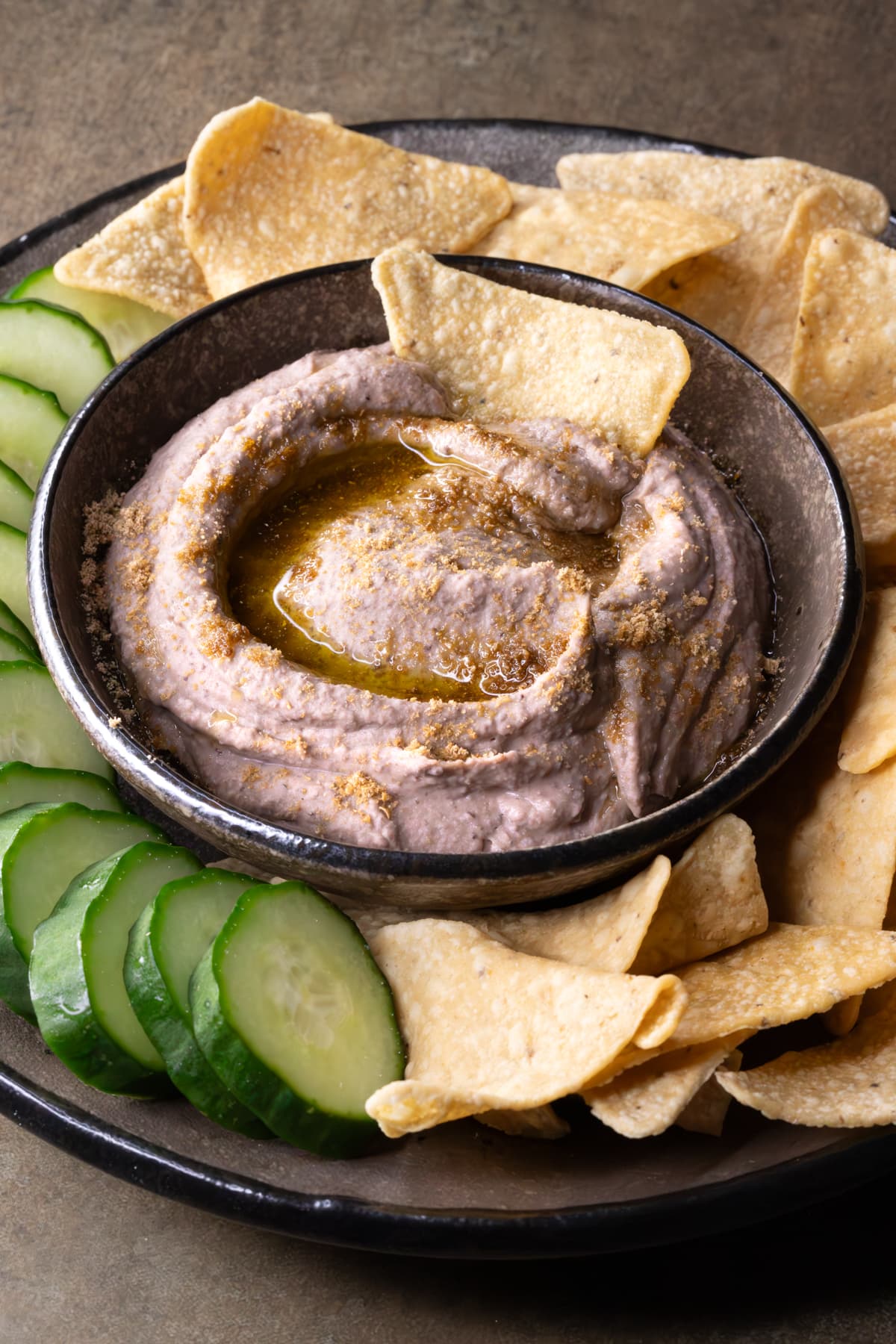 Black bean dip in a bowl with cucumber slices and tortilla chips