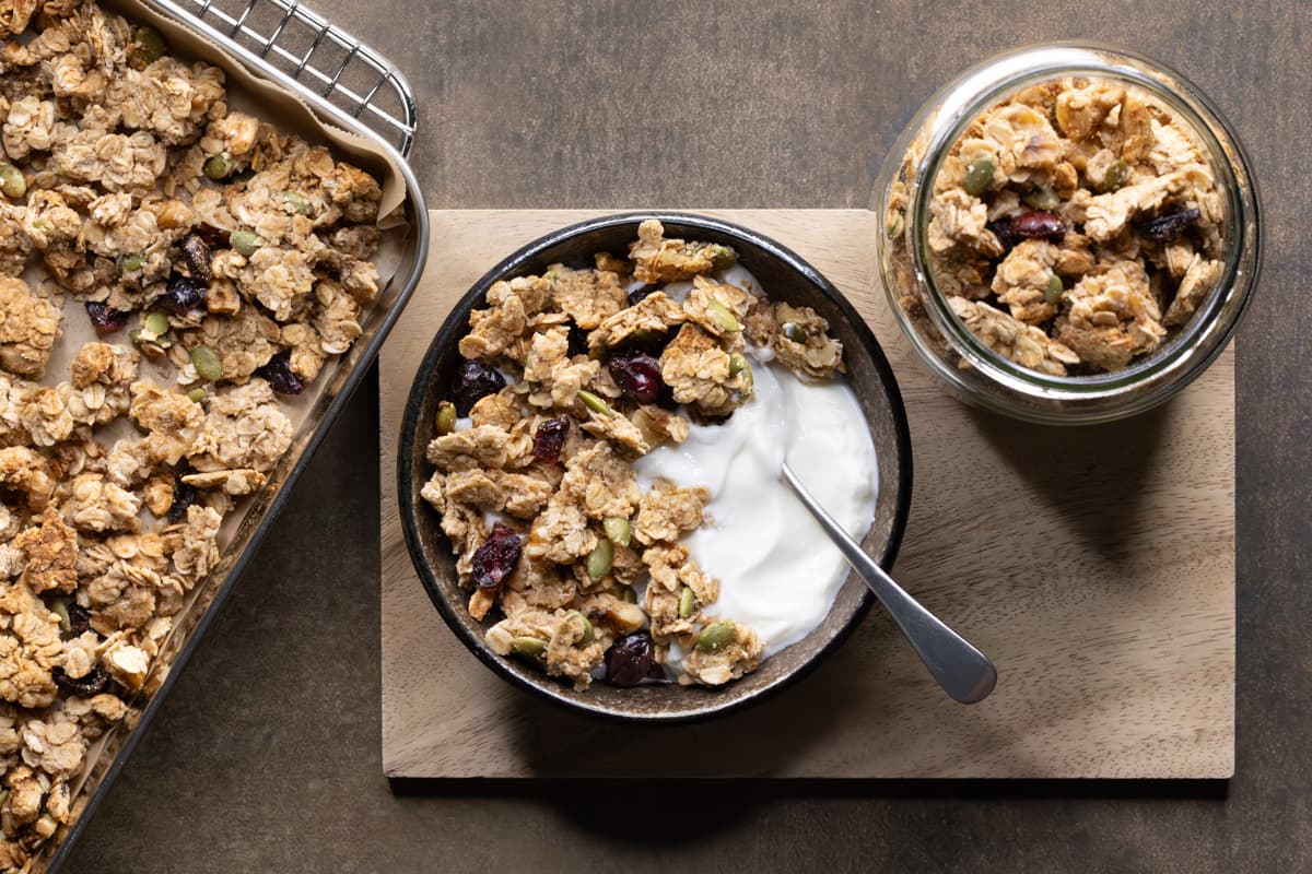 Granola clusters baked on a tray and served in a bowl with yoghurt